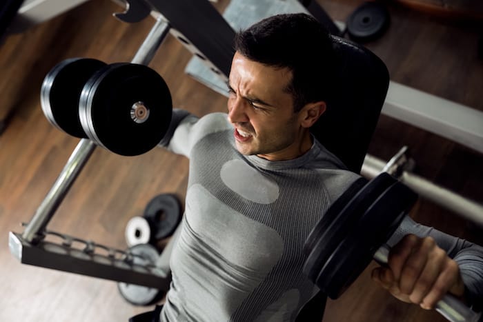 Strong man holding huge weight and working bench press